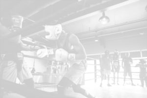 Two boxers in the ring sparring with Undisputed members watching.